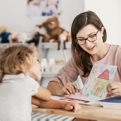 A professional child education therapist having a meeting with a kid in a family support center.