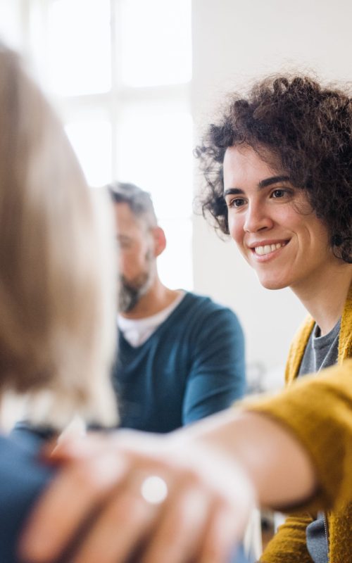 Men and women sitting in a circle during group therapy, supporting each other. Serious men and women sitting in a circle during group therapy, supporting each other.