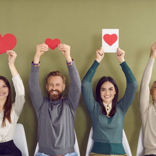 Portrait of smiling diverse people in row on green background show heart shapes make gesture. Happy men and women colleagues demonstrate love and care, feel grateful thankful. Charity concept.