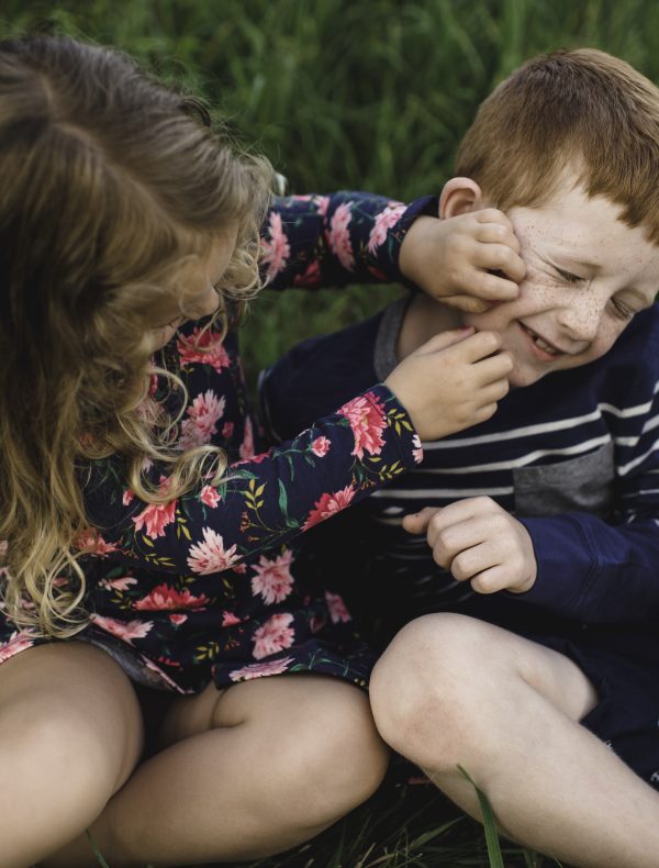 Boy and sister play fighting in field