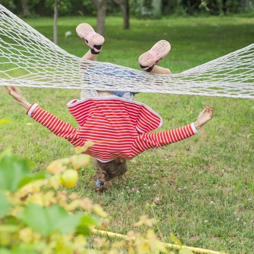 Child girl falling from hammock, spring garden background Child girl falling from hammock, spring garden background