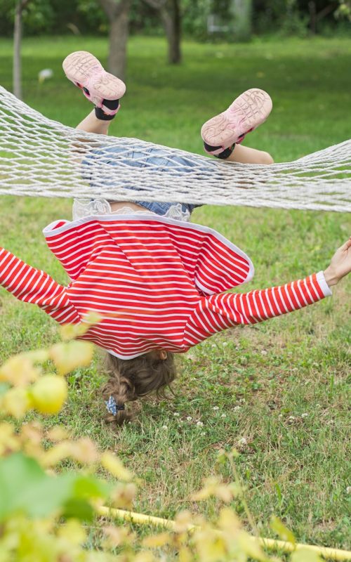 Child girl falling from hammock, spring garden background