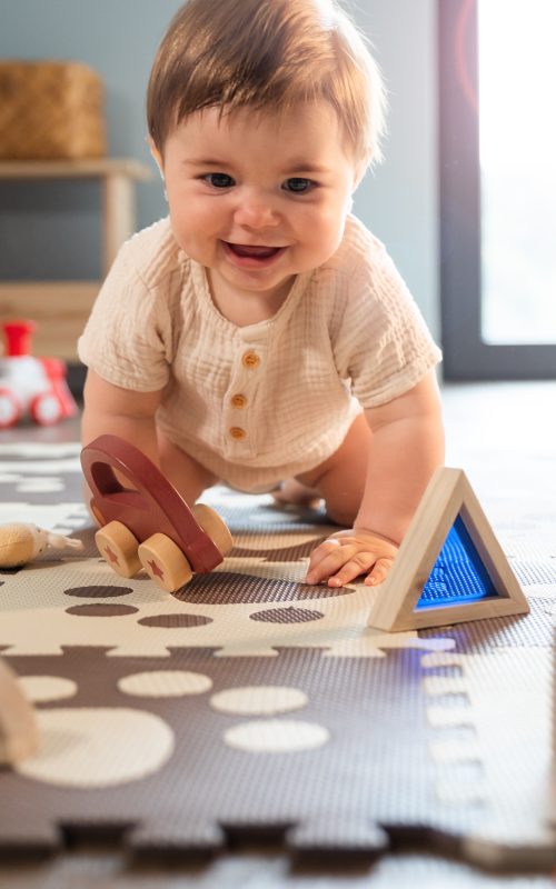 Cute happy baby boy playing toys in his child room