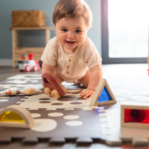 Cute happy baby boy playing toys in his child room