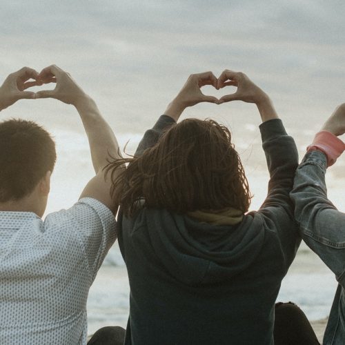 Friends making love heart hands at the beach