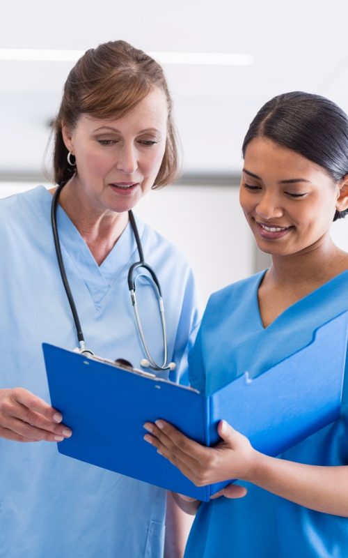 Nurse and doctor discussing over clipboard