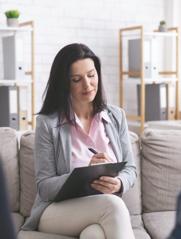 Professional psychologist taking notes at couple meeting with patients Professional psychologist taking notes at couple meeting with patients