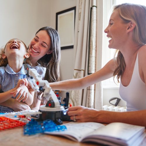 Same Sex Female Couple Making Robot From Kit With Daughter In Bedroom At Home Together Same Sex Female Couple Making Robot From Kit With Daughter In Bedroom At Home Together