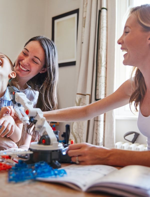 Same Sex Female Couple Making Robot From Kit With Daughter In Bedroom At Home Together Same Sex Female Couple Making Robot From Kit With Daughter In Bedroom At Home Together