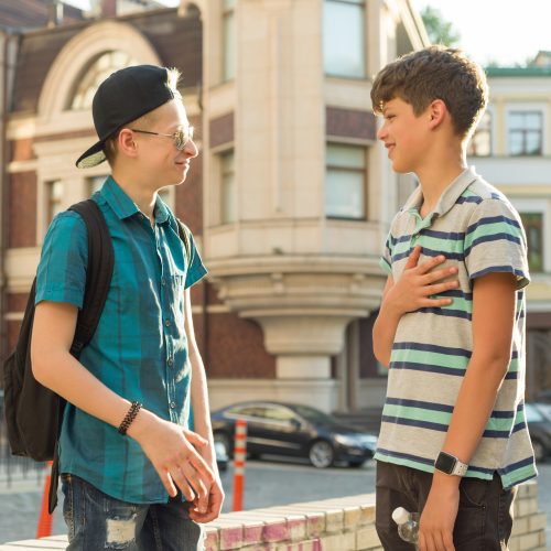 The friendship and communication of two teenage boys is 13, 14 years old, city street background The friendship and communication of two teenage boys is 13, 14 years old, city street background