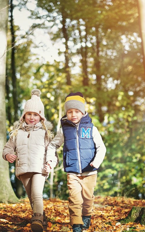 Two happy children walking through the forest